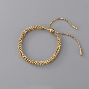 Detail of adjustable golden braided wheat chain bracelet with round bead slide clasp
