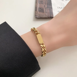 Bracciale a catena cubana dorata con una piastra identificativa rettangolare lucida