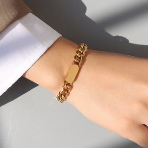 Bracciale a catena cubana placcato oro con piastrina rettangolare liscia su polso femminile