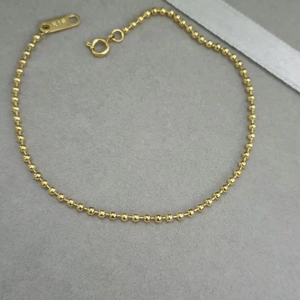Minimalist 18K gold 4mm bead chain bracelet with spring clasp on grey velvet