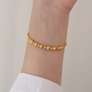 Golden titanium steel bead bracelet featuring alternating frosted and polished spheres