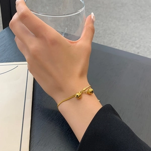 Minimalist double bell pendant chain bracelet in 18K gold finish on female wrist