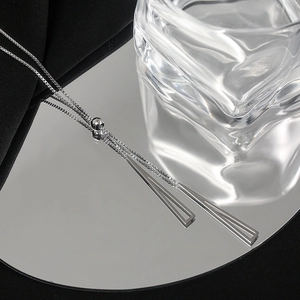 Macro shot of silver triangle pendant necklace with adjustable box chain on mirror