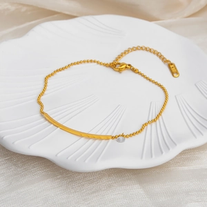 18K gold plated bead anklet with a smiling bar and zircon pendant on a silk background