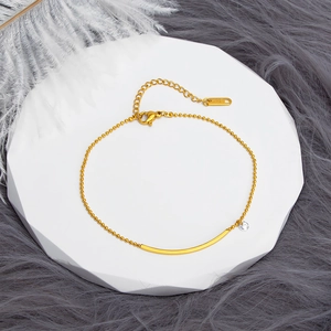 Detailed view of an 18K gold-plated beaded anklet with curved bar and zircon stone charm
