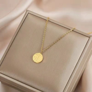 Collier en acier titane doré avec pendentif Fu sur un écrin de luxe soyeux