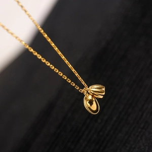 Elegante goldene Lotus-Halskette mit poliertem Perlenanhänger auf schwarzem Hintergrund