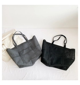 Detalle de bolsas tote de malla con múltiples bolsillos y asas tejidas en gris y negro