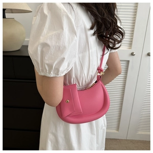 Pink half-moon shoulder bag with matching coin purse shown on a model in a cozy interior