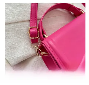 Détail d'un sac à main rouge rose avec boucle dorée polie et bandoulière réglable