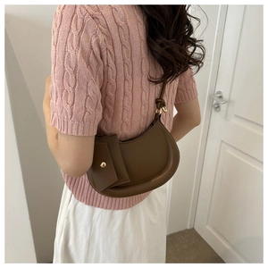 Detailed side view of a brown leather hobo bag with a decorative pouch and knot strap