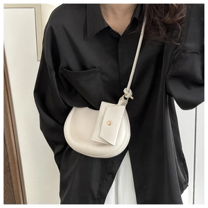 Chic beige half-moon crossbody bag with a knot-detail strap and mini coin pouch accessory