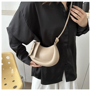 Beige crescent shoulder bag styled with a minimalist outfit and detachable pouch