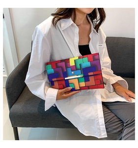 Detail einer bunten geometrischen Clutch mit goldenem Verschluss auf weißem Hemd