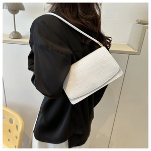 Close-up of a white crocodile embossed rectangular shoulder bag with gold hardware detail