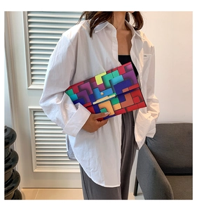 Nahaufnahme einer bunten geometrischen Patchwork-Umschlagtasche mit goldenem Metallverschluss