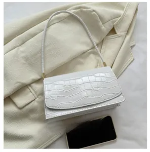 White crocodile embossed baguette bag showing size comparison with a mobile phone