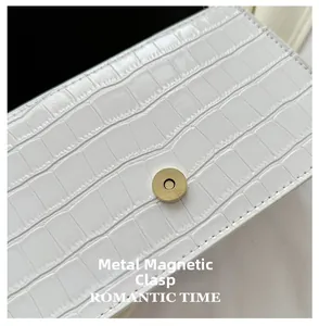 Close-up of golden magnetic clasp on white crocodile pattern stone texture handbag