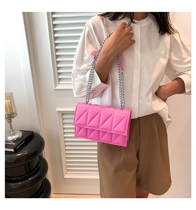 Detail of pink quilted shoulder bag with silver chain strap and geometric stitching