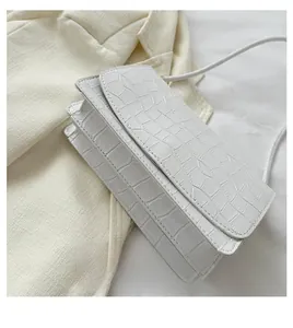 Macro view of white faux leather with crocodile texture and stitching on crossbody bag