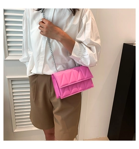 Detail of bright pink square bag with triangular quilted texture and silver chain strap