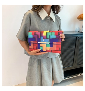 Bunte geometrische Clutch-Tasche mit silbernem Metallverschluss von einem Model gehalten