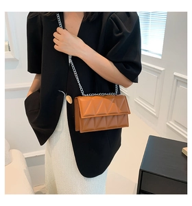 Close-up of caramel brown quilted crossbody bag with silver chain strap on model