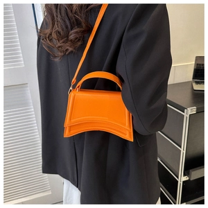 Détail d'un sac à main sablier orange avec base incurvée et texture en cuir lisse