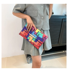 Detailansicht der bunten geometrischen Umschlag-Clutch, gehalten von einem Modell in Grau