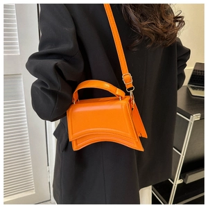 Vue latérale du mannequin portant un sac sablier orange vif avec un tailleur noir