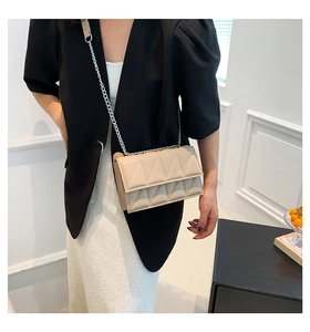 Detail of beige crossbody bag featuring 3D triangle quilting and silver chain strap