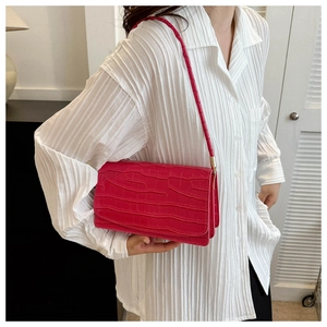 Model wearing a bright rose red crocodile pattern rectangular crossbody bag on white shirt