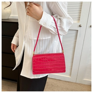 Close-up of bright pink faux crocodile skin texture and gold hardware on shoulder bag