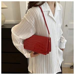 Detail of red crocodile pattern shoulder bag with gold hardware on white shirt