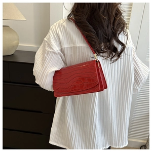 Model wearing a red crocodile pattern baguette bag with stylish gold metal accents
