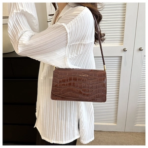 Close-up of a brown croc-embossed shoulder bag with a rectangular flap and gold hardware
