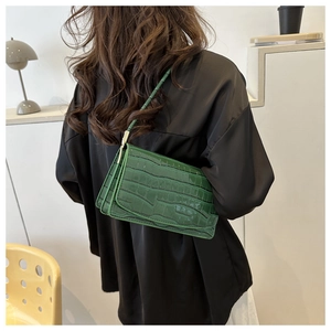 Detail of dark green crocodile pattern shoulder bag with glossy patent leather texture