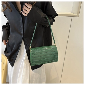 Detail of green faux crocodile skin texture on a glossy rectangular shoulder bag