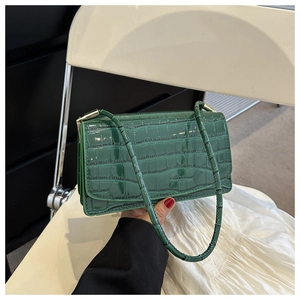 Close-up of deep green crocodile embossed glossy faux leather on rectangle shoulder bag