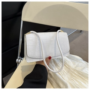 Close-up of white crocodile pattern shoulder bag with sleek golden hardware details
