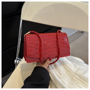 Detail of red patent leather shoulder bag with crocodile pattern and glossy finish