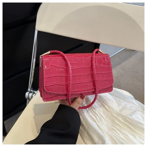 Close-up of bright pink faux leather shoulder bag with crocodile pattern and metal clasp