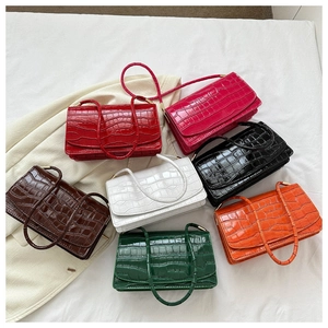 Flat lay of small patent leather crossbody bags with crocodile texture in seven colors