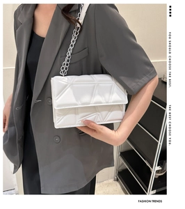 Detail of white quilted crossbody bag with thick silver chain on a casual blazer outfit