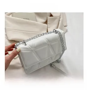 Detail showing the white quilted texture and silver chain strap of the crossbody bag