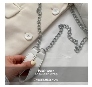 Detail of silver chain and white leather strap on a stylish crossbody quilted bag