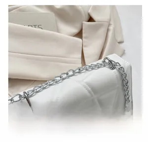 Detail shot of white geometric quilted leather handbag with premium silver chain strap