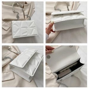 Detailed view of white quilted crossbody bag with silver chain strap and interior storage