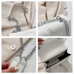 Detail view of white quilted faux leather bag with silver chain strap and magnetic closure