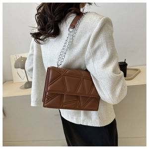 Close-up of brown quilted shoulder bag with geometric stitching and silver chain strap
